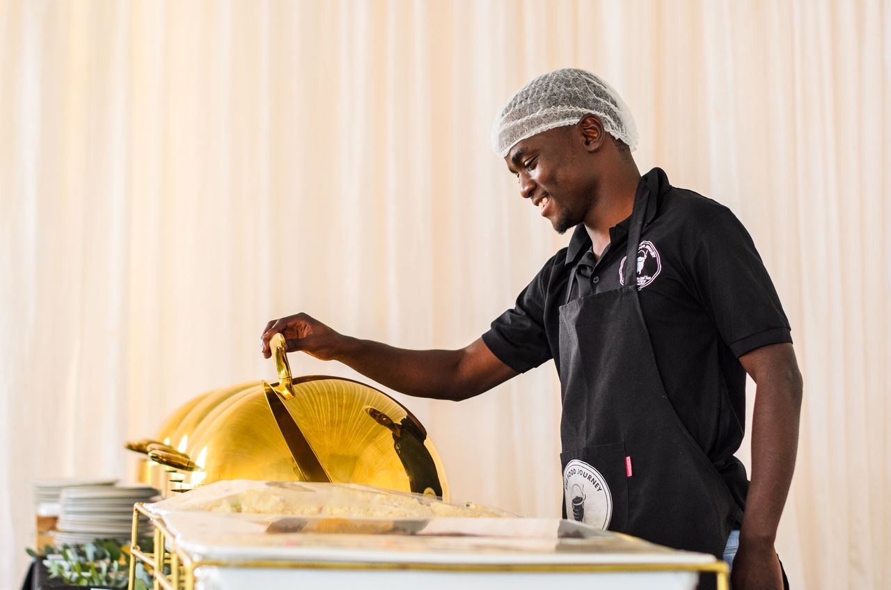 A cheerful caterer serves food at a buffet, showcasing professional catering service.