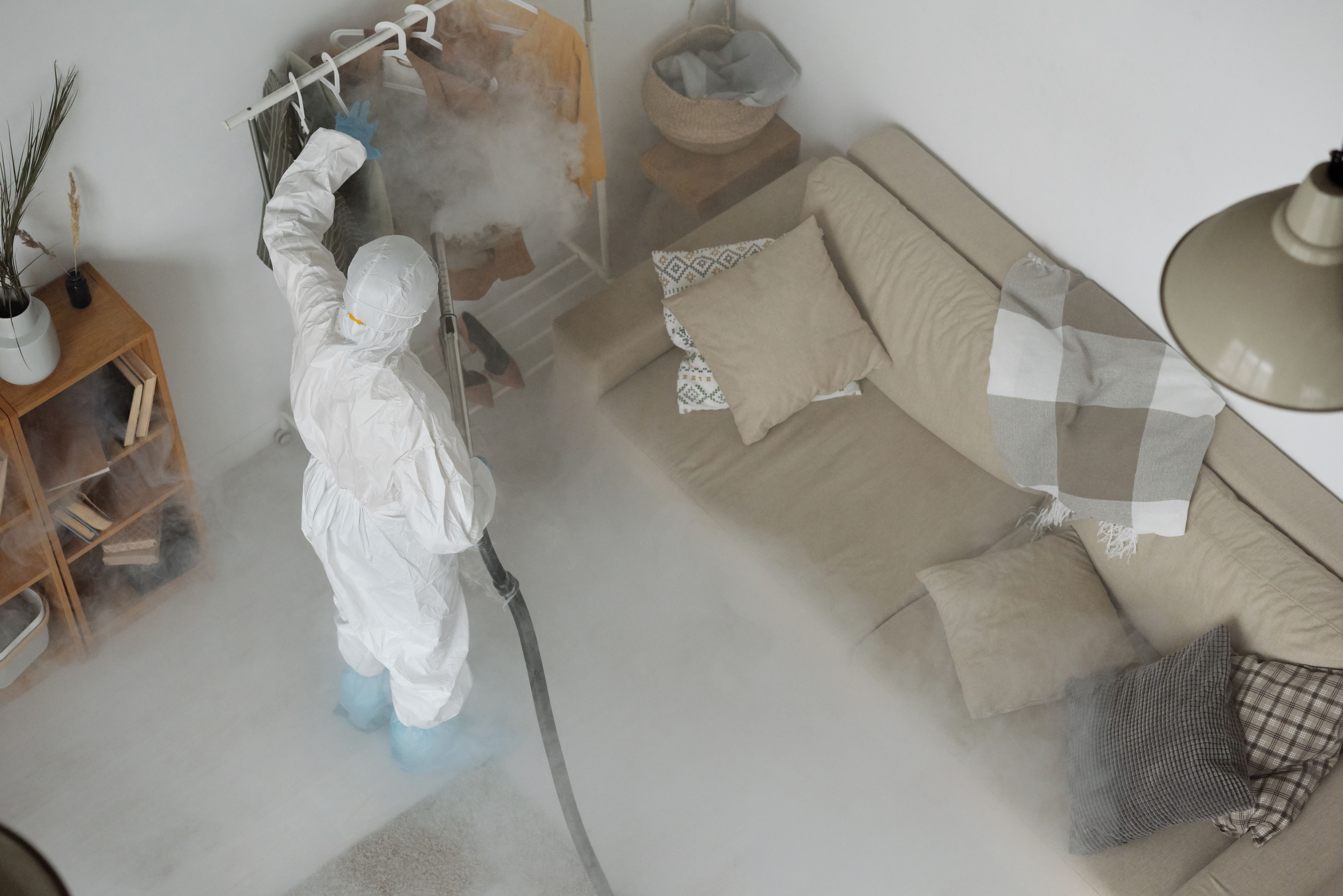 Home Person in protective gear sanitizing home interior for COVID-19 safety.
